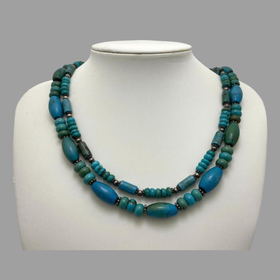 Main photo of vintage 2 strand turquoise neclklace displayed on a white display stand against a mid grey background. The beads are neatly in their 2 rows - shorter inside, longer outside and forward facing.