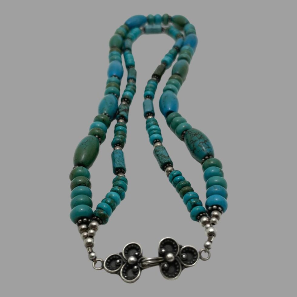 Photo of 2 strand necklace laid on a flat surface with the clasp area in the foreground. The clasp is unusual and very pretty with a 3 petalled flower on each side.