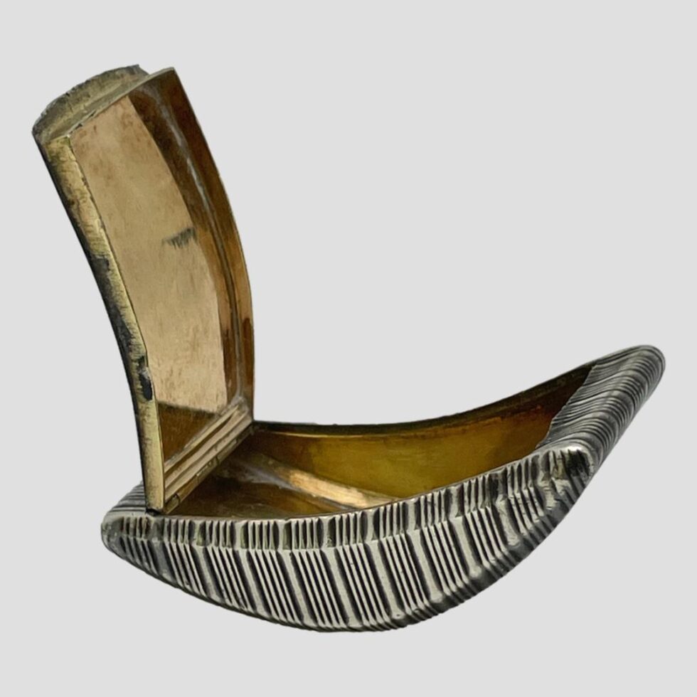 Photo of snuff box shown open with the lid upright to the left side. As mentioned in description, the box leans over to side of open lid steadying the box as displayed here. The gilt interior is visible here.