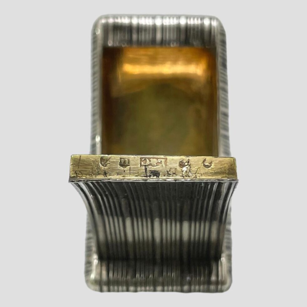 Photo of snuff box displayed open with the open lid in the centre foreground. The hallmark is visible on the inside edge of the lid.