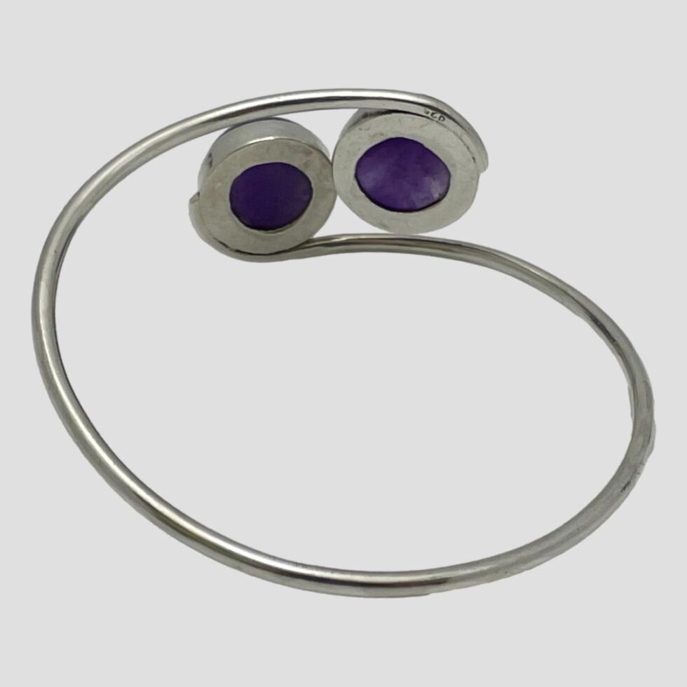 Photo of the amethyst bracelet seen from the back showing the setting for the 2 amethyst cabochons and the curving design feature of the silver band.