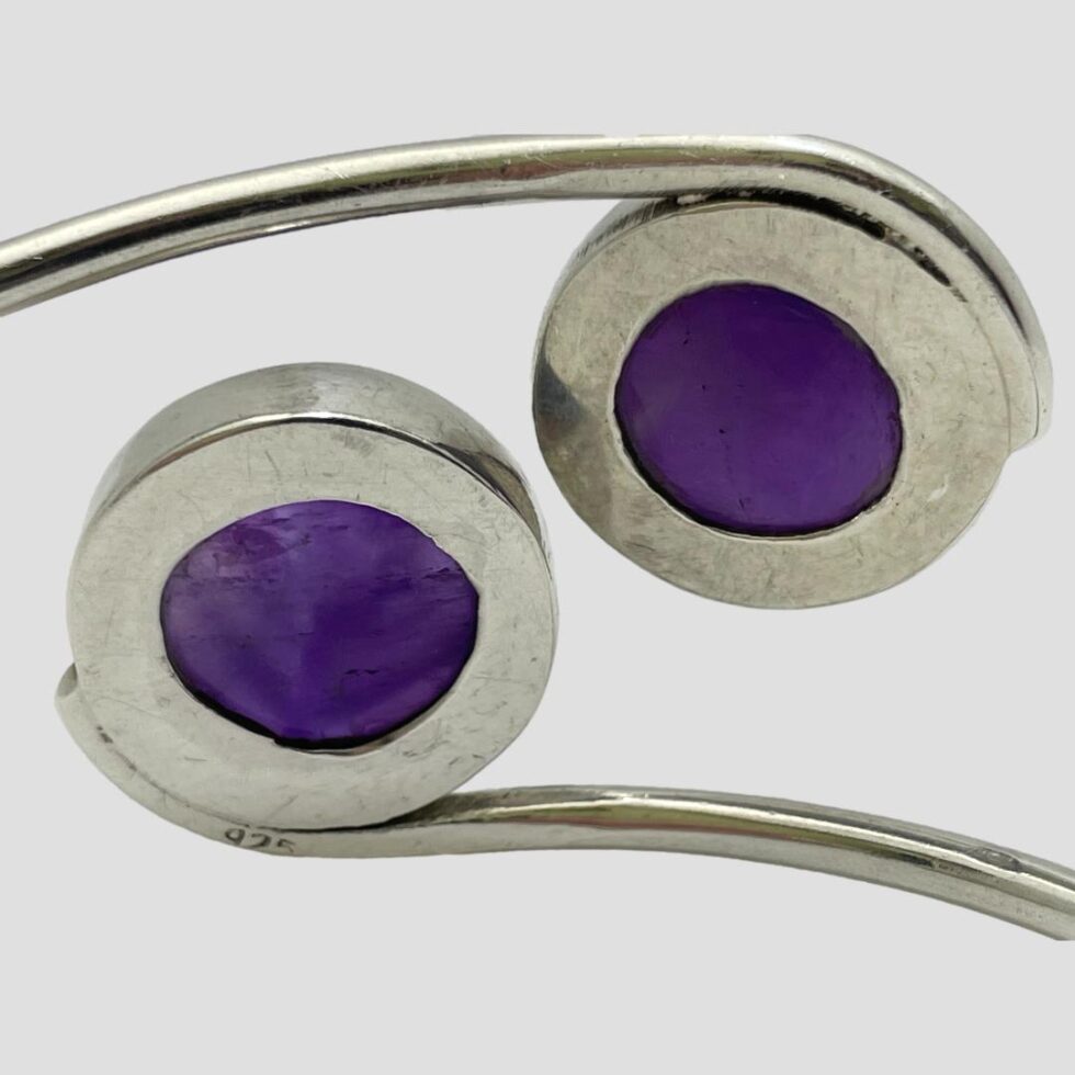 Close up photo of the back of the bracelet this time showing the backs of the amethyst cabochons. The silver is nice and solid for the stones. The hallmark of 925 is visible on the lower band.