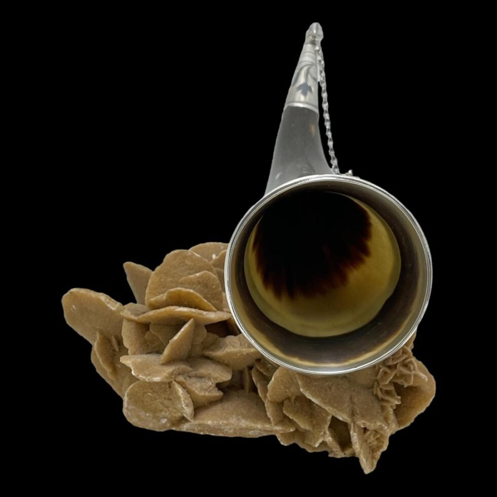 Photo of Russian horn drinking vessel displayed on a rock of natural desert sand rose and looking into the mouth of the vessel. As the horn has a curved tip, the end of the horn is visible in the background.
