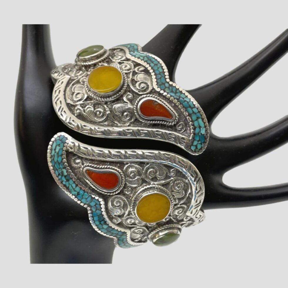 Photo of chunky hinged silver bracelet displayed across the palm of a black display stand with the front opening of the bracelet at centre.