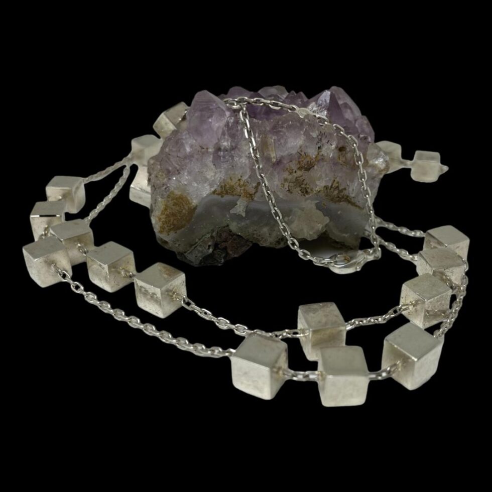 Photo of chain displayed swirled around a small rock of amethyst with the clasp end of chain resting over the rock and to the front.