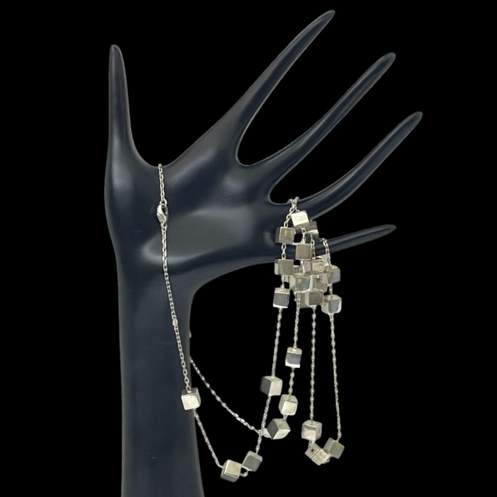 Photo of Georg Jensen Aria necklace thing time displayed dangling from a black hand display stand. The clasp end is to the left whilst the rest of the cubed chain is lopped around the last 2 fingers.