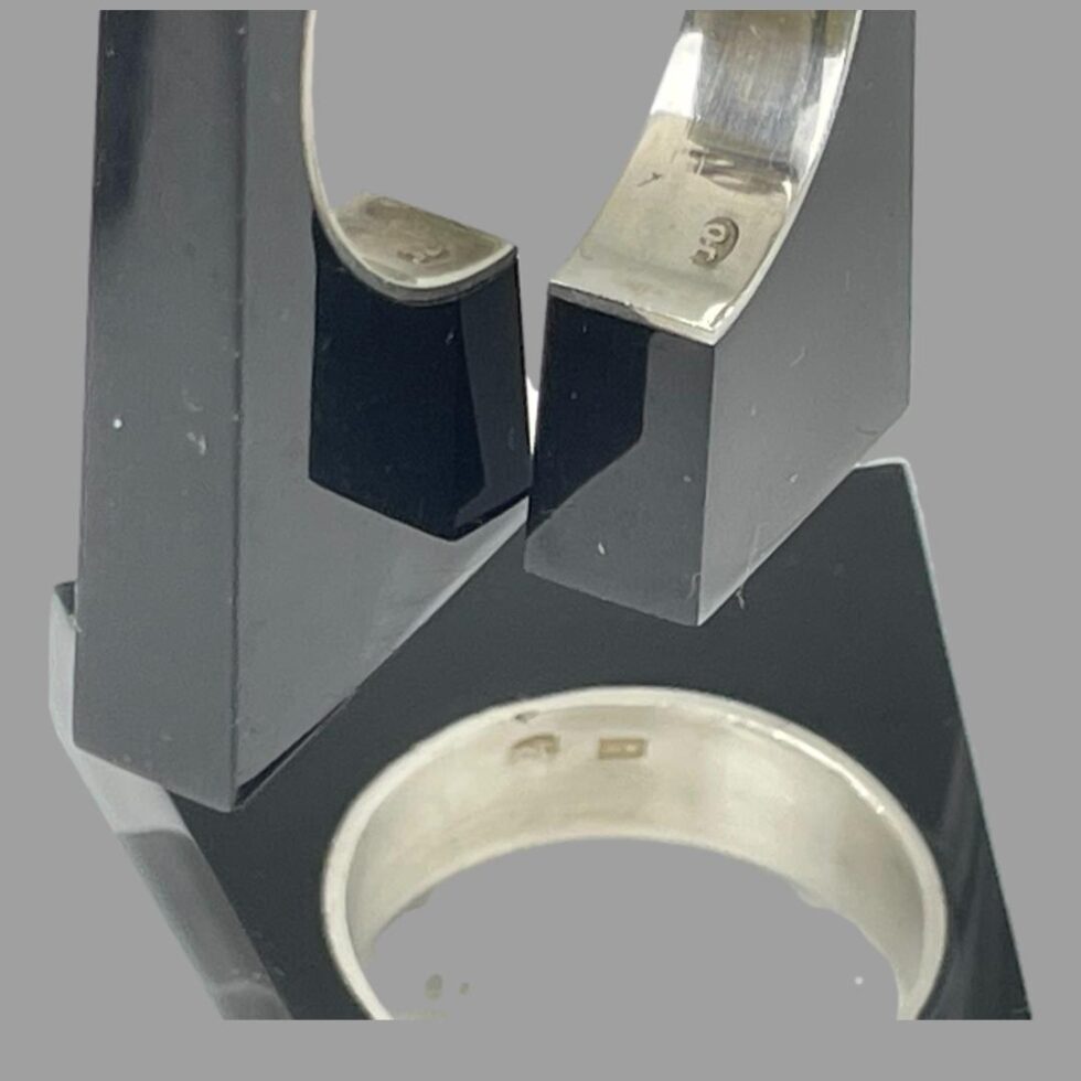 Close up photo of the hallmarks on each piece. Ring is at bottom whilst earrings are dangling above.