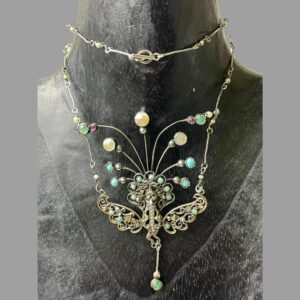 Main photo of antique French peacock necklace displayed on a black wooden display stand and forward facing. The chain has been wound round the neck once so the clasp area is at the top centre. The peacock takes quite a large area of this necklace with its width and length. It would look fabulous worn with a low fronted dress.