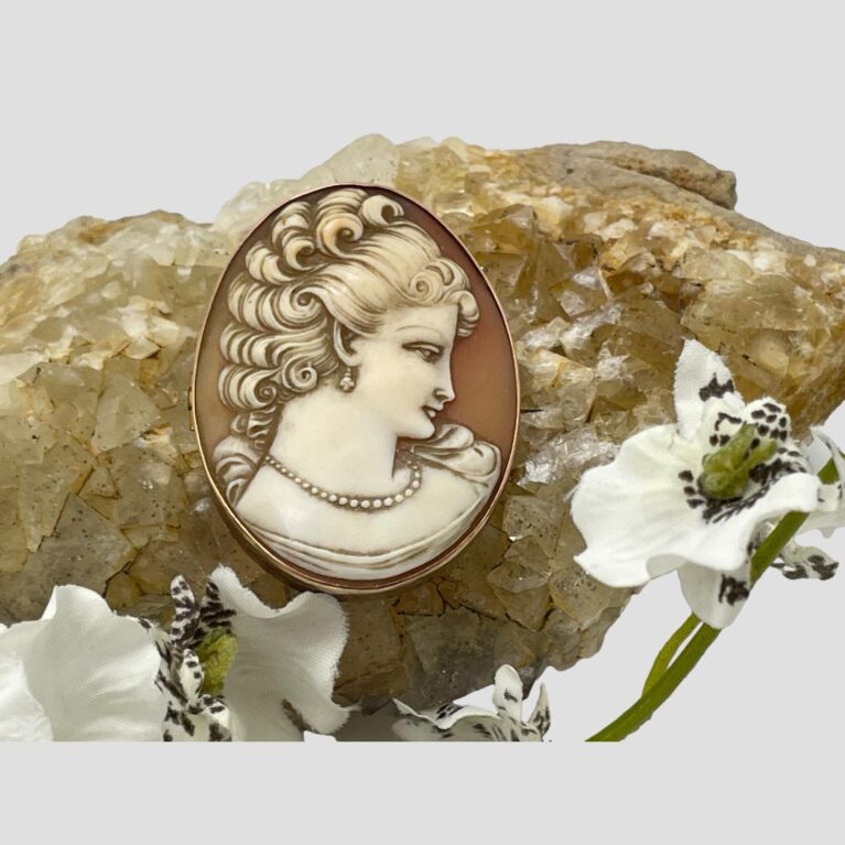 Main photo of antique 9kt gold cameo. The cameo is displayed balanced on a rock of natural river quartz which is a light brown/beige colour which compliments the colour of the cameo which is a pale terracotta background with creamy/beige profile of a lady. The carving of the lady is beautifully done. She has an exquisite serene look and is facing slightly with head down as if averting the gaze of someone - very dreamy piece! Ah! Hence the Dreamy.