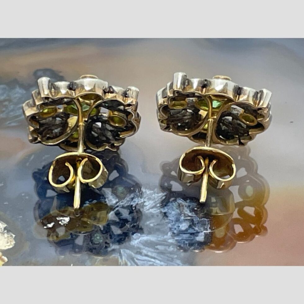 Photo of the back of both peridot diamond studs with butterflies in place. From this angle, it is possible to see the dividing line of the gold and silver.