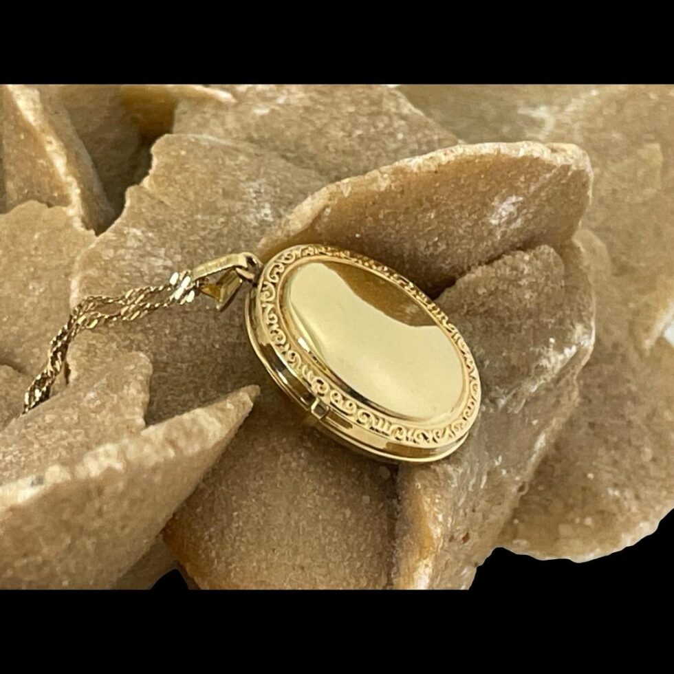 Photo of the back of cameo locket displayed on rock of desert sand rose and showing the back of locket which has a blank centre area.