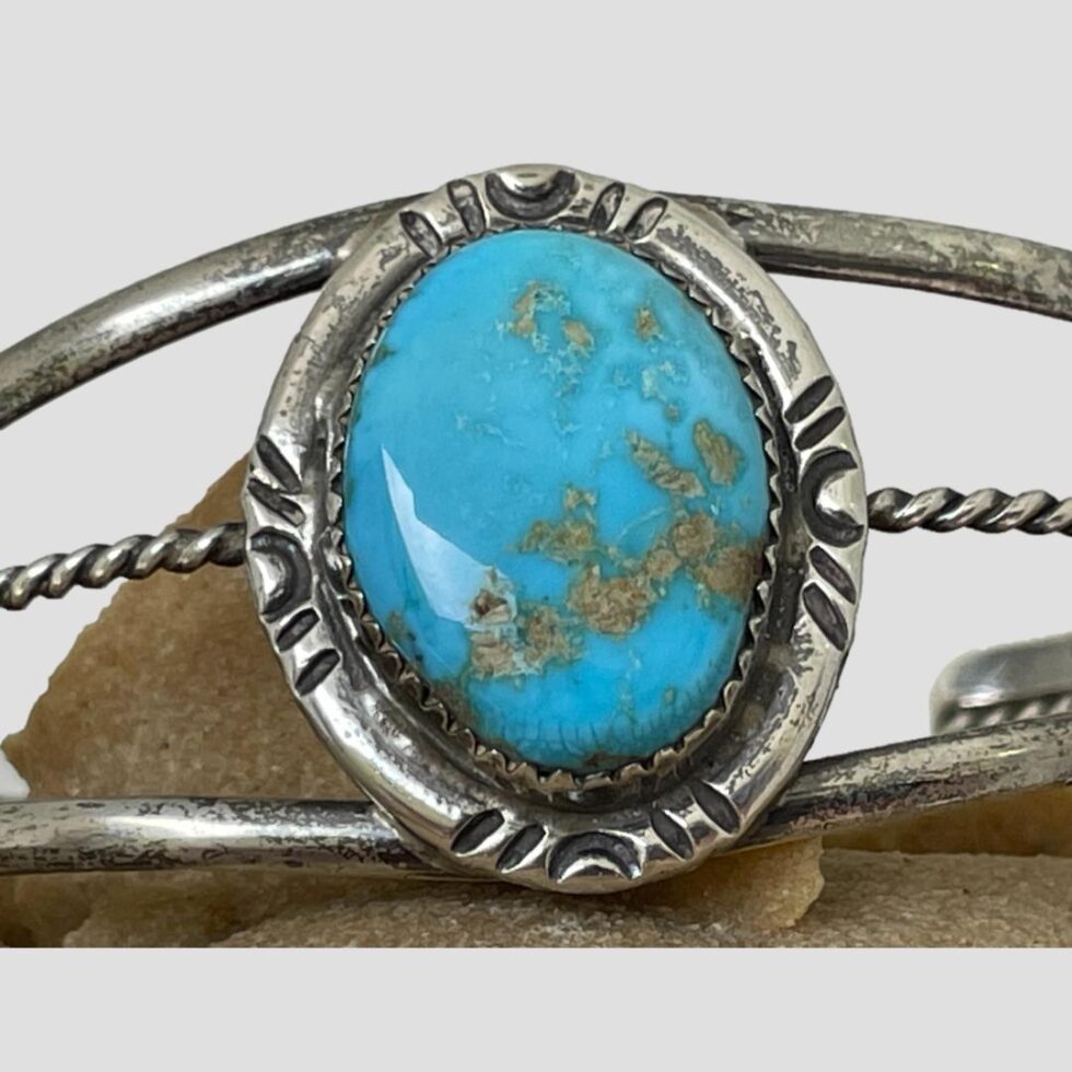 Close up photo of the centre of the cuff bracelet showing the beautiful colour of the turquoise stone and its golden inclusions.