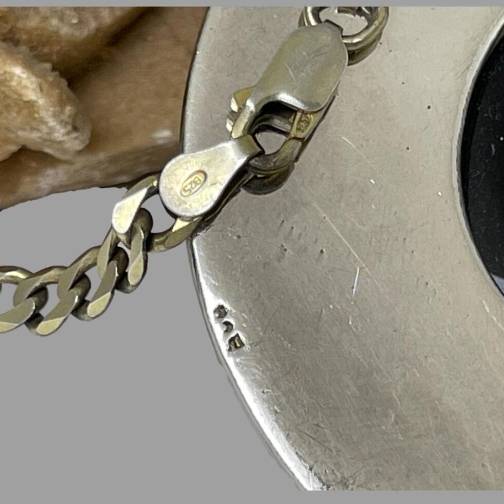 Close up photo of the hallmarks, 2 on either end of the chain and the 925 on the edge of the huge pendant.