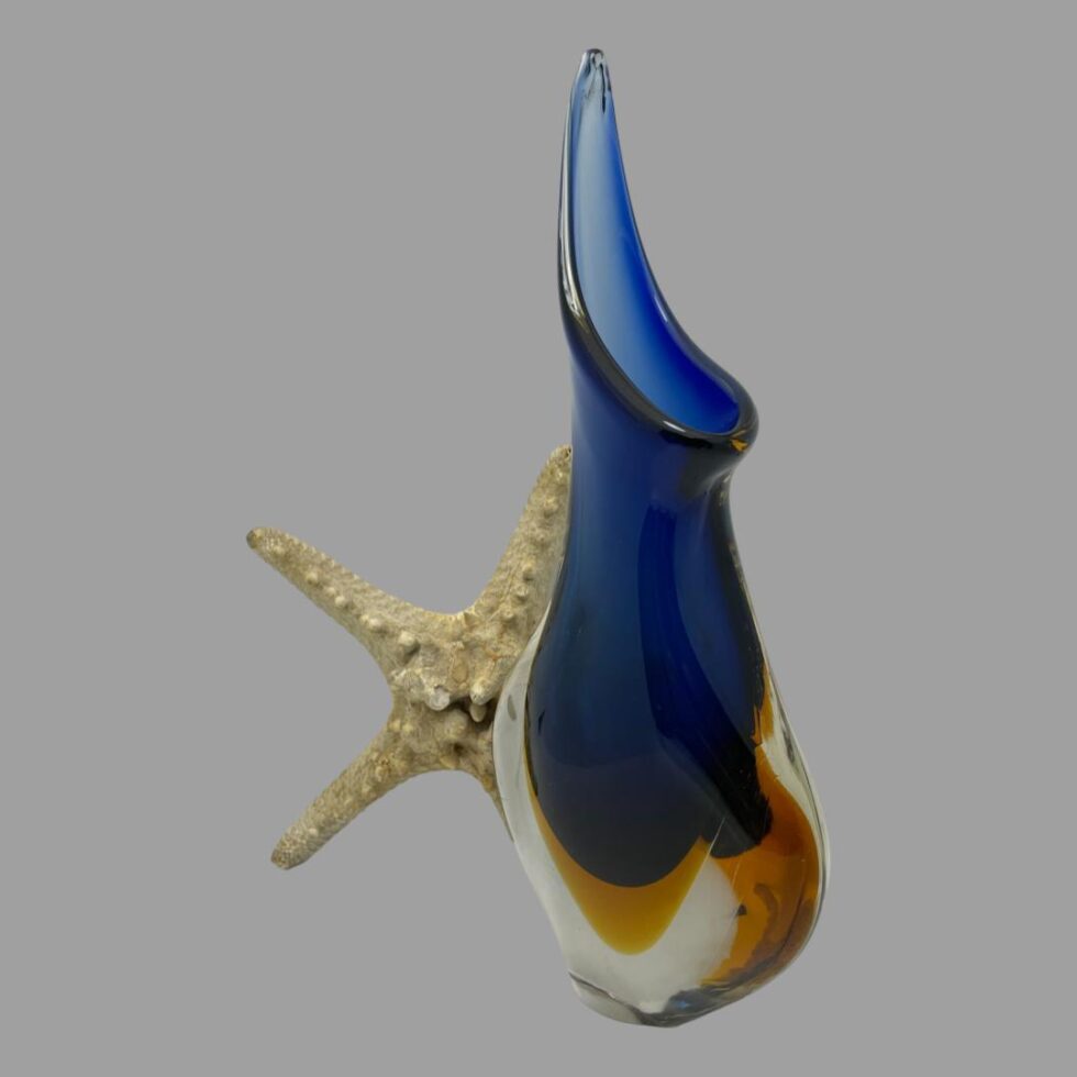 Photo of Murano blue sommerso vase this time turned slightly to the side showing the mouth with the extended glass section in the background. The starfish is still behind the vase.