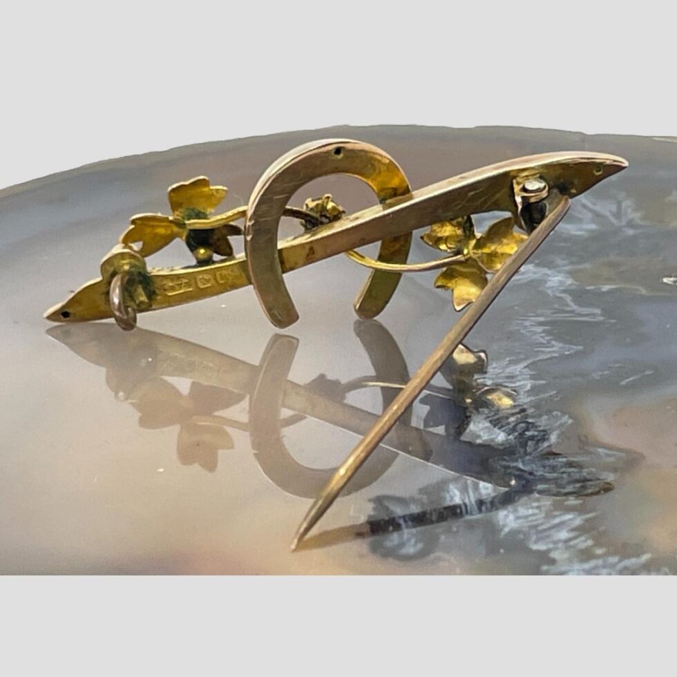 Photo of Edwardian gold sapphire brooch displayed from the back. It is shown upright being propped up by its own pin.