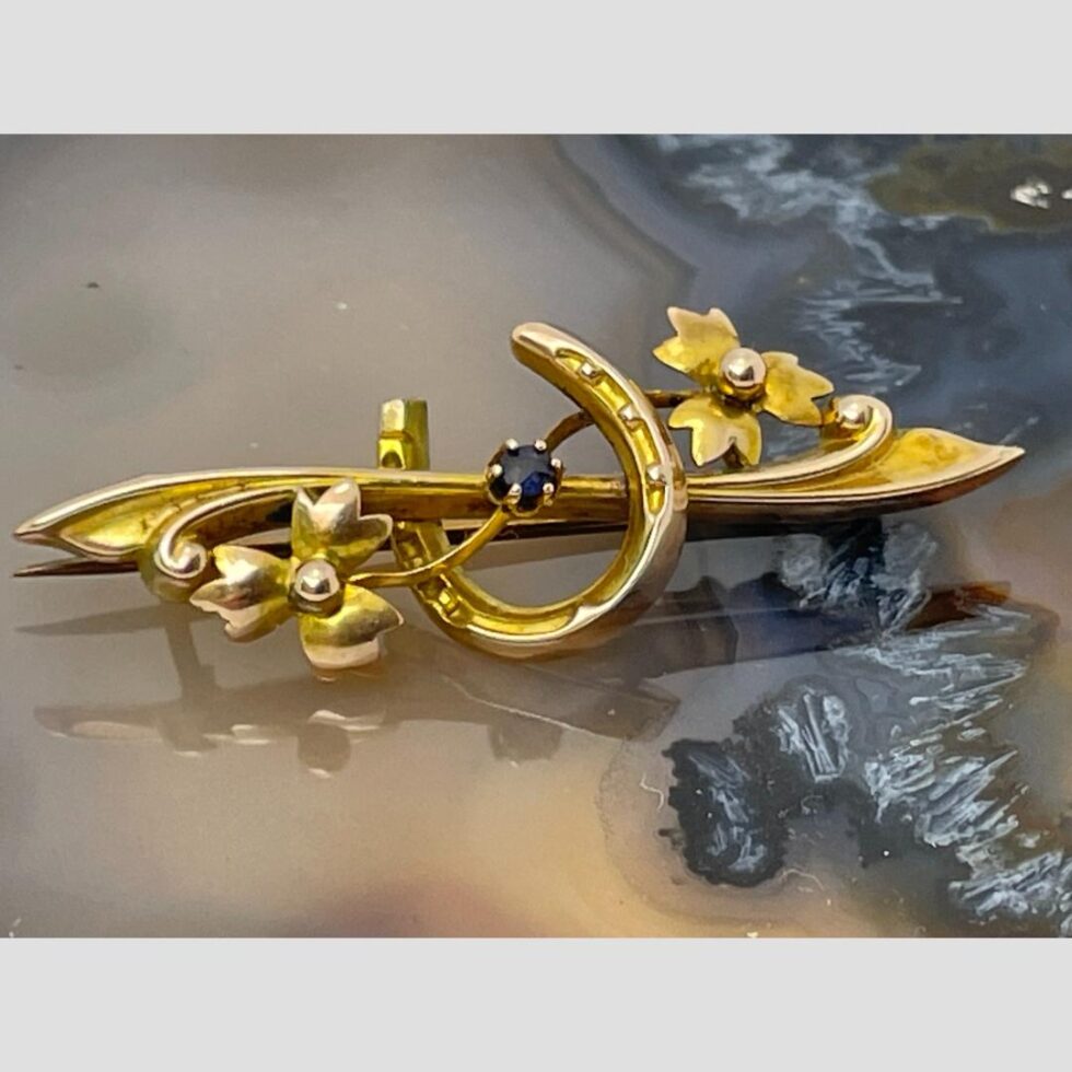 Photo of brooch laid flat on a slice of agate this time with the horseshoe the wrong way up or with the luck stuck!