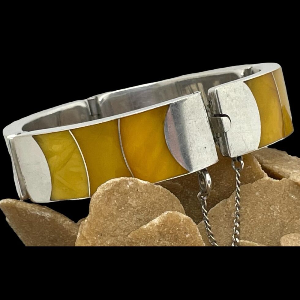 A closer look at the Modernist silver amber bracelet still displayed on top of the desert sand rose rock. The graduating shades of the egg yolk amber are more clearly visible here.