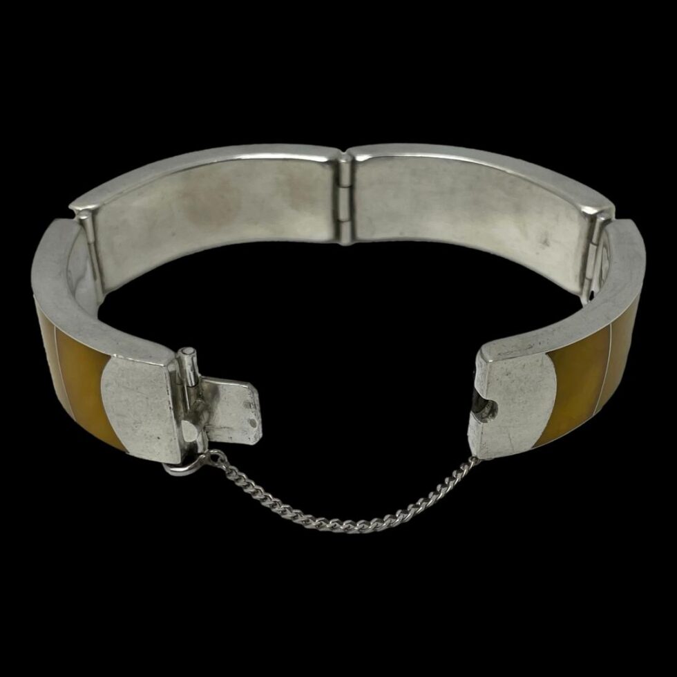 Photo of bracelet laid on a flat surface with the clasp in the foreground shown wide open with safety chain stretched almost fully.