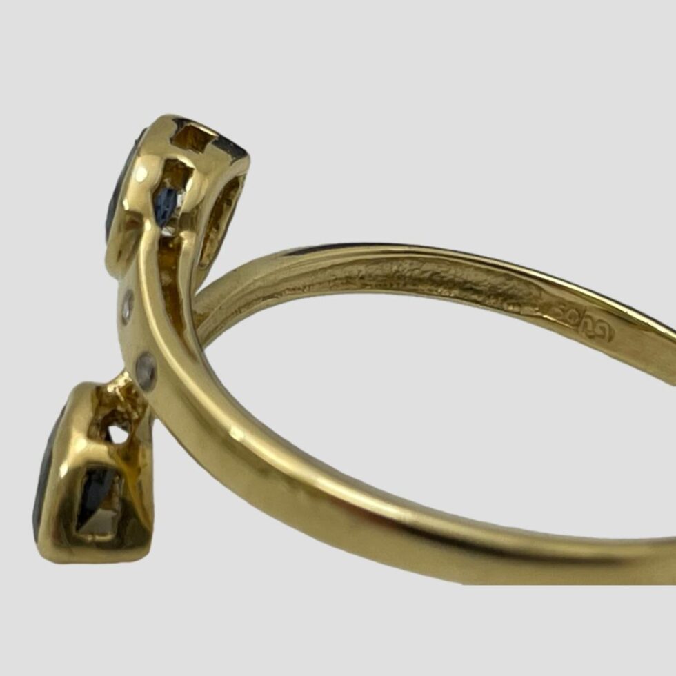 Photo of gold sapphire diamond ring with ring front facing left. The hallmark is visible to the inside band.