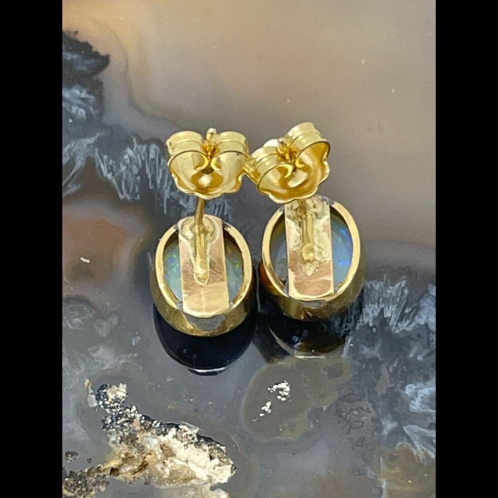 Photo of both gold opal stud earrings displayed side by side and face down showing the back of the opal setting and earring design frame.