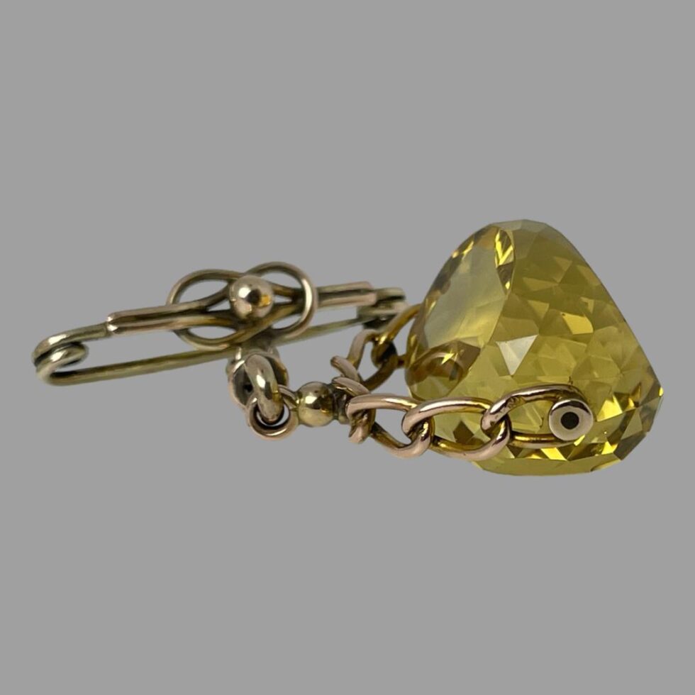 Photo of the fob laid flat and seen with citrine stone to the right. The hallmark on the chain link nearest to the stone is just visible.