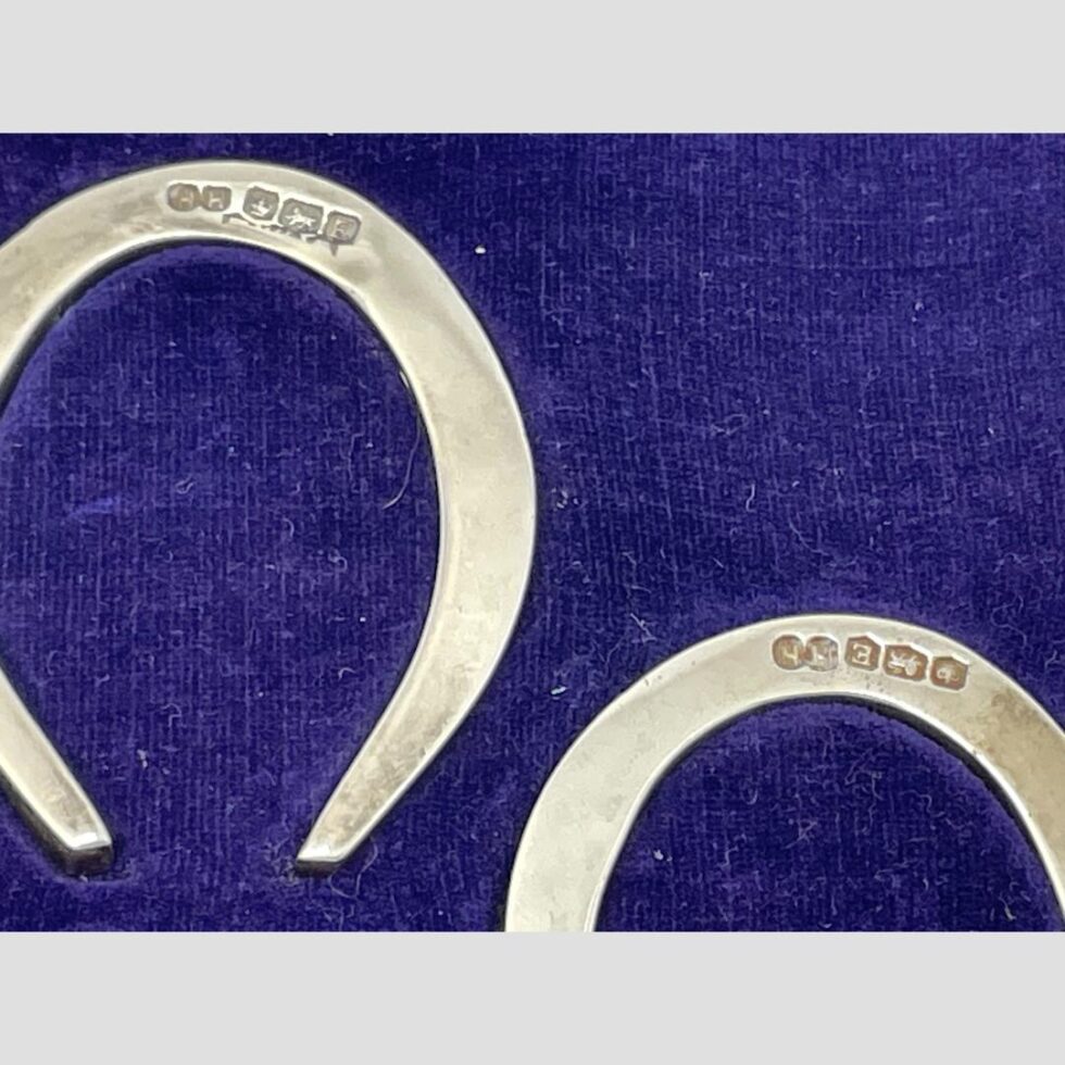 A close up of the hallmarks on both horseshoes which are displayed in side the fitted case,