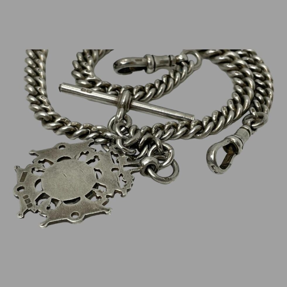 Close up photo of some of the hallmarks - back of fob, one end and one side of dog clips and 2 box hallmark on the T-bar. Some of the lion passant stamps on the chain links are visible.