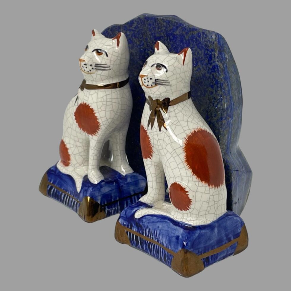 Photo of Staffordshire cats still displayed side by side in front of a rock of natural lapis this time the cats are positioned towards bottom left corner and facing left.