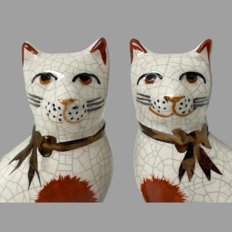 Close up photo of the Staffordshire cats showing both from the shoulders up. They both appear to have a contented look with the one on right especially having a more pronounced smile.