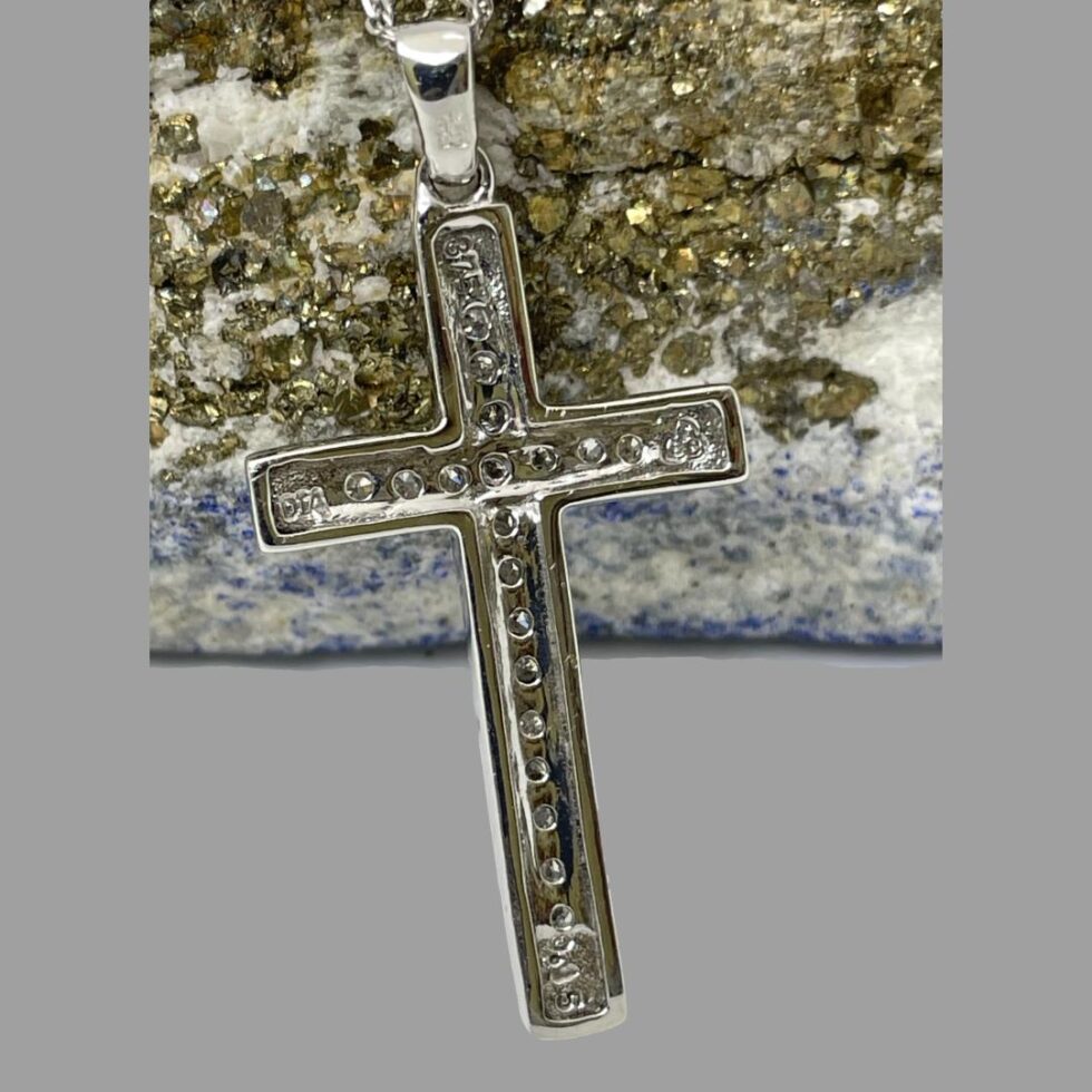 Photo of the back of white gold diamond cross. There is a hallmark to each tip of the cross.