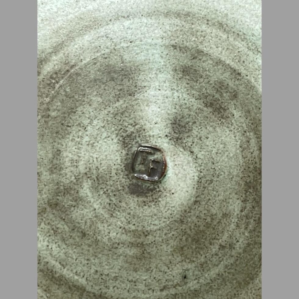 Close up photo o the artists initials TF within its own frame at the centre of the base.