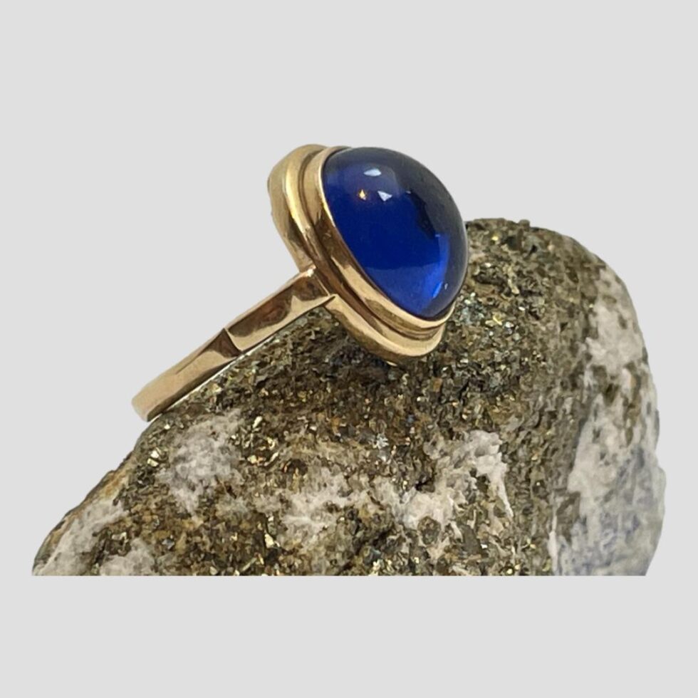 Photo of gold &blue spinel ring still displayed on top of a rock of natural lapis with the ring front facing to the right. The ring is seen in close up here.