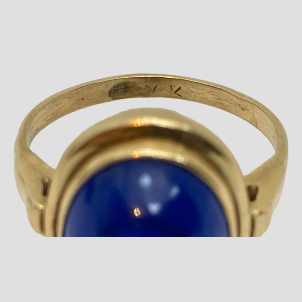 Photo of gold and blue spinel ring zooming into the barely visible hallmark on the inside band.
