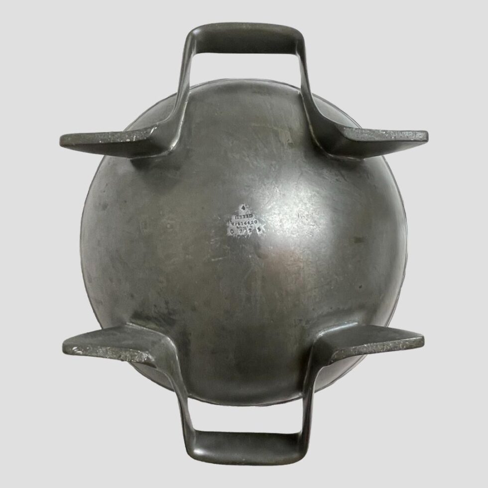 Photo of the base of Knox Tudric pewter bowl showing the incredible aesthetics in the design. The handles are forged from 2 single lengths of pewter shaped like stands for the bowl to sit on. The makers details are visible on the base of bowl.