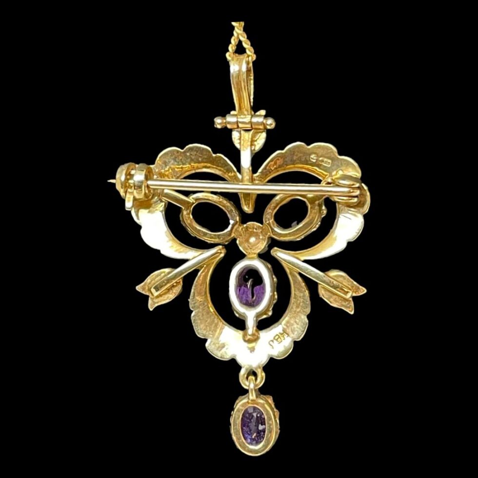 Photo of back of gold pendant brooch showing the pin and the hallmark to the top right and makers initials on the lower right.