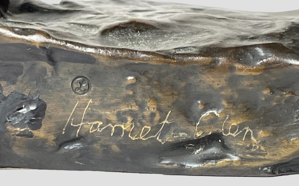 A close up photo of the artists signature to the side of base by back leg.