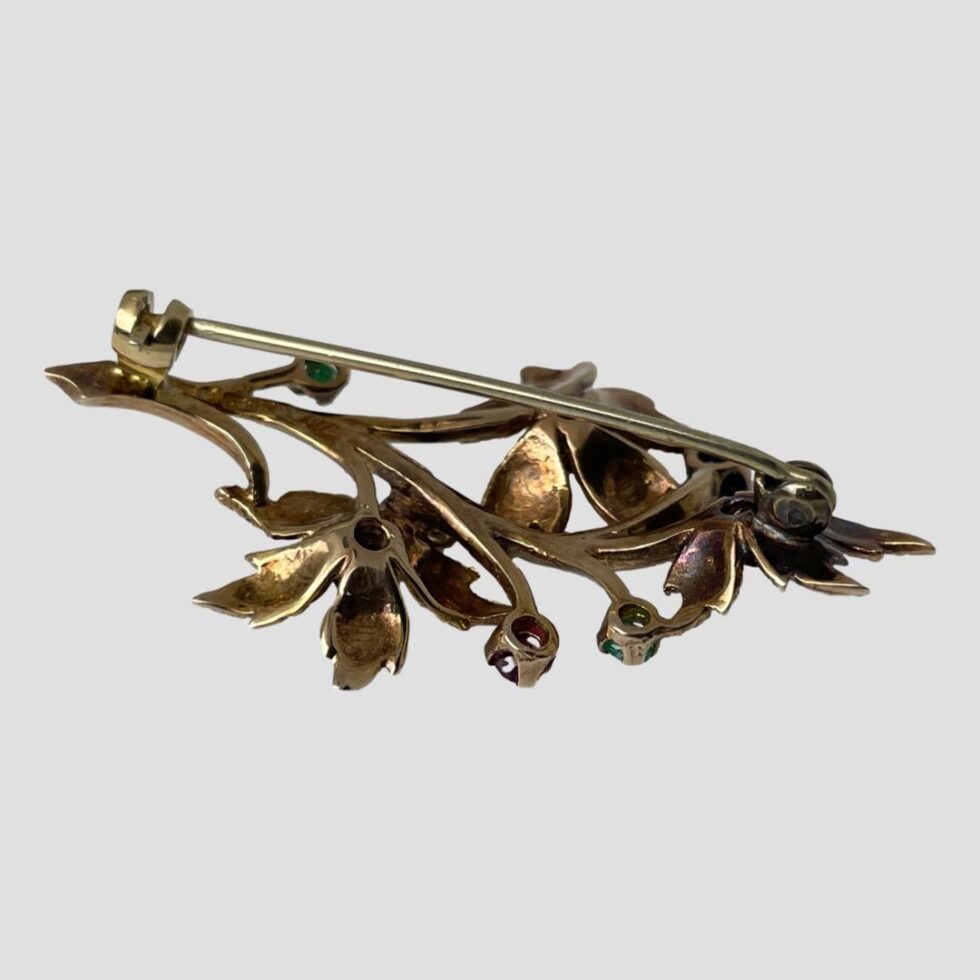 Photo of brooch displayed on a flat surface and shown face down revealing the pin which is closed.