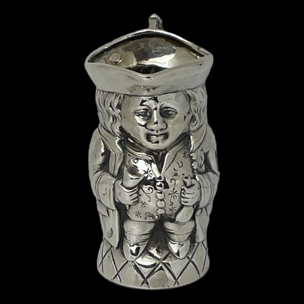 Photo of Edward silver Toby Jug seen from the front. This Toby is holding a cone shaped goblet in one hand and possibly a tobacco or snuff pouch in the other.