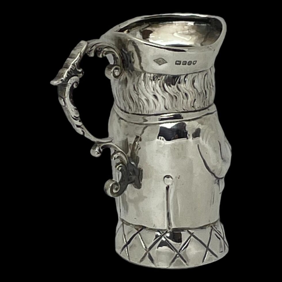 Photo of Toby jug this time the front is facing the top right corner so side and back is displayed. The British import hallmark is visible around the rim of the tricorn hat.