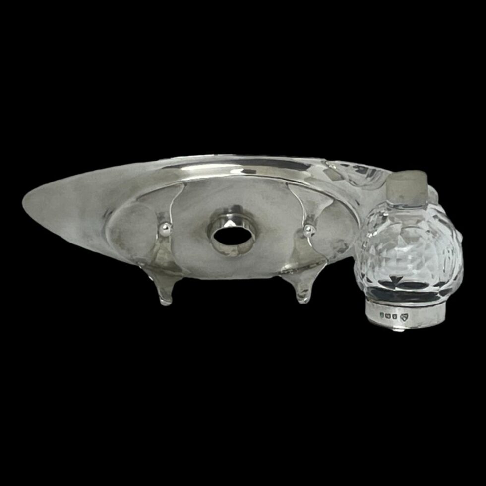 Photo of both the inkwell and silver stand displayed with their bases on display. The inkwell is upside down with the crystal extension at the top. The slot where the inkwell sits is visible to the centre of the stand.