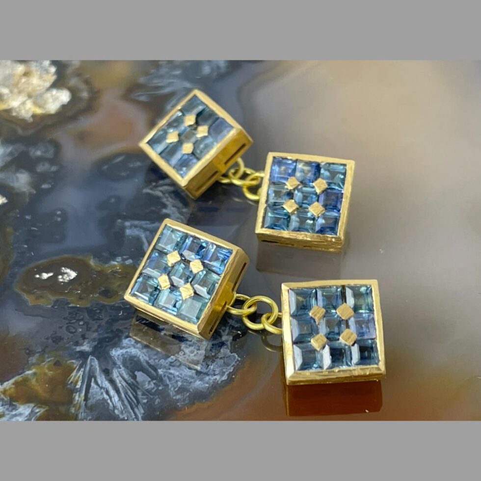 Photo of both cufflinks displayed horizontally one above the other with both sides of sapphire faces on show.
