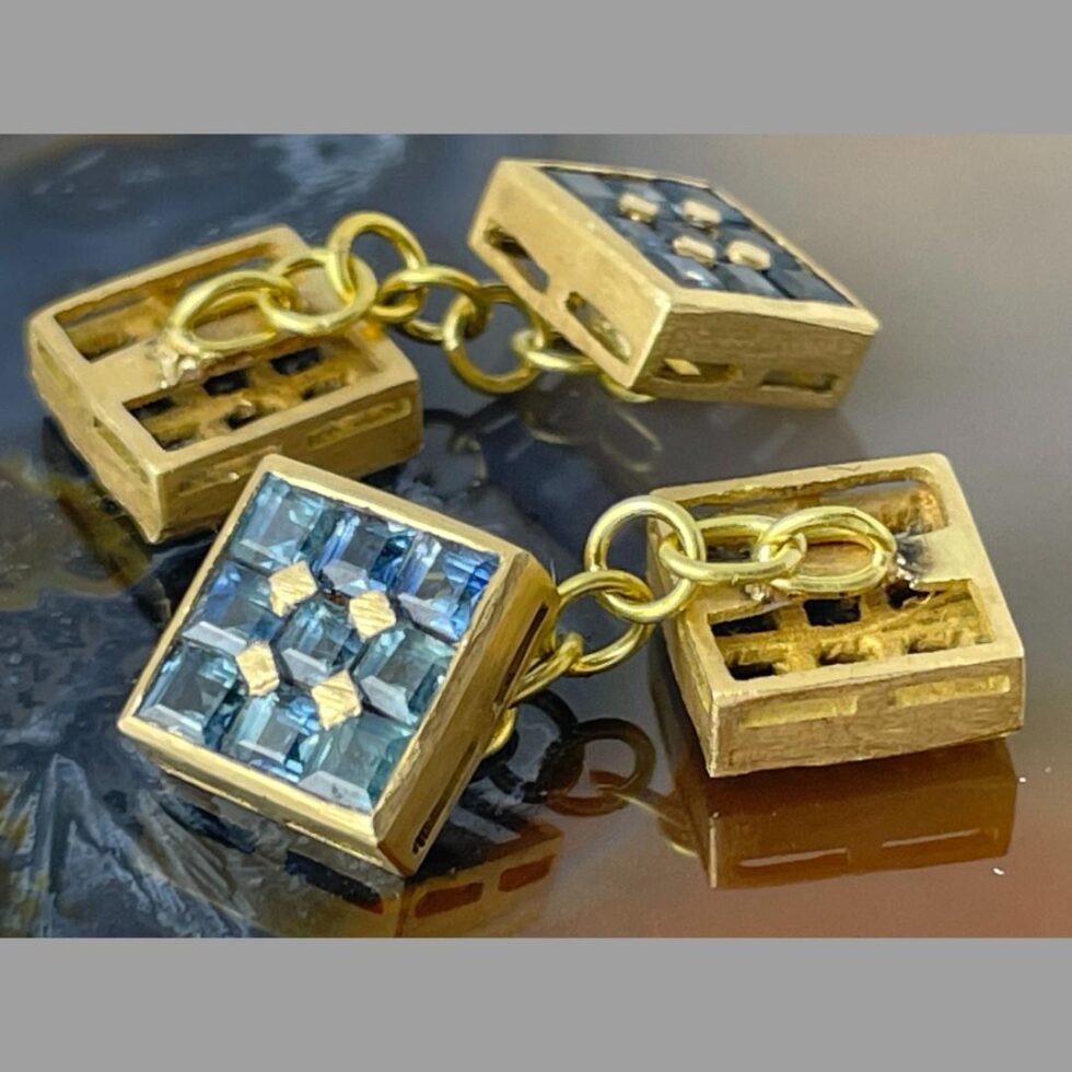Photo of both cufflinks displayed on the agate slice and viewed in close up. They are horizontally laid with one sapphire side up and other face down.
