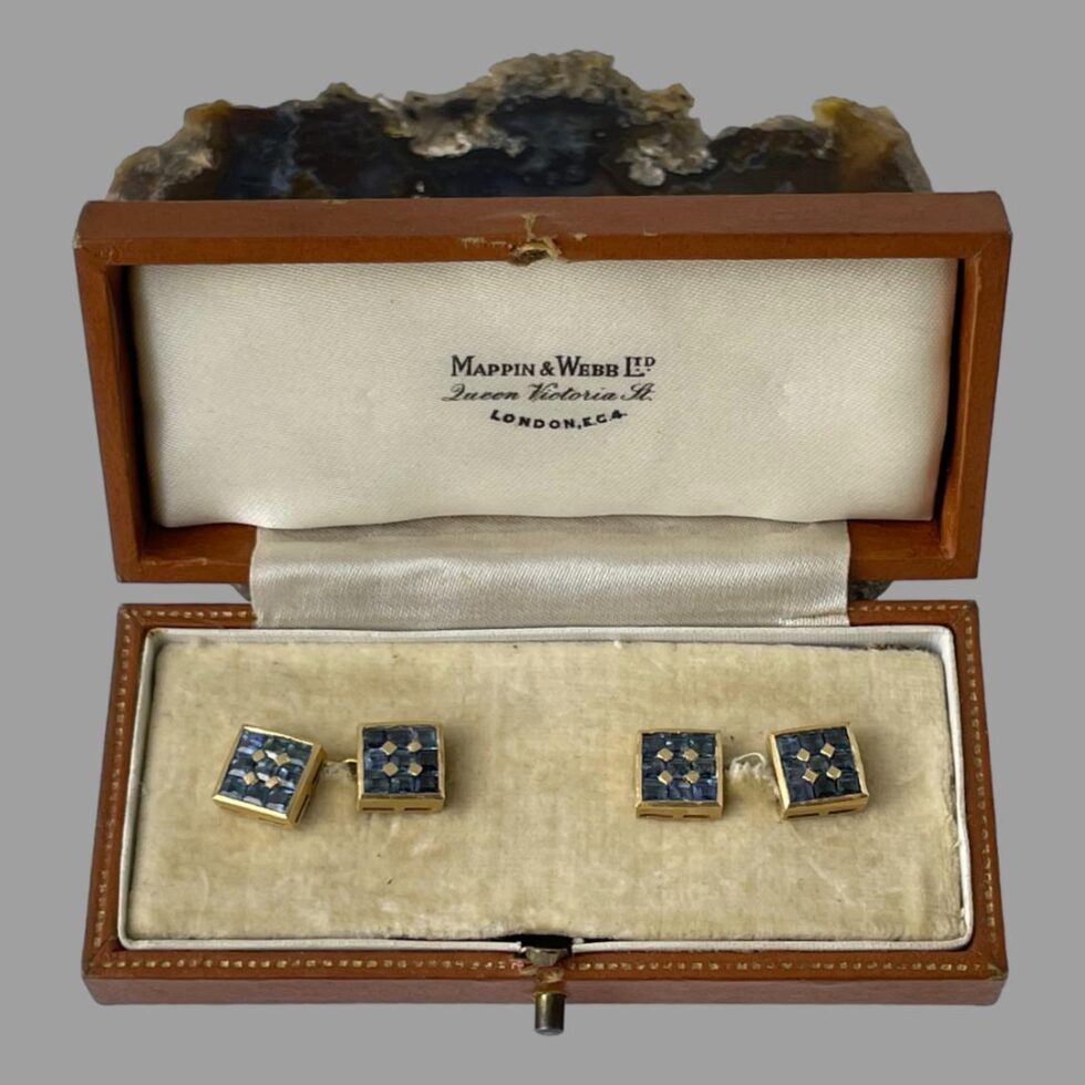 Main photo of 18kt gold sapphire cufflinks displayed inside the old Mappin & Webb box. We are looking directly down at the cufflinks which are shown with sapphire sides up. The Mappin & Webb stamp is visible to the silk inside of box lid and a little of the agate slice is visible at the top of photo.