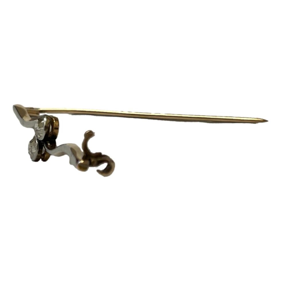 Photo of brooch from a side angle with the pin open and horizontal across centre of page. In the foreground is the 'click to close' clasp. There is a hook that the pin sits in with an additional click close section to secure the pin.