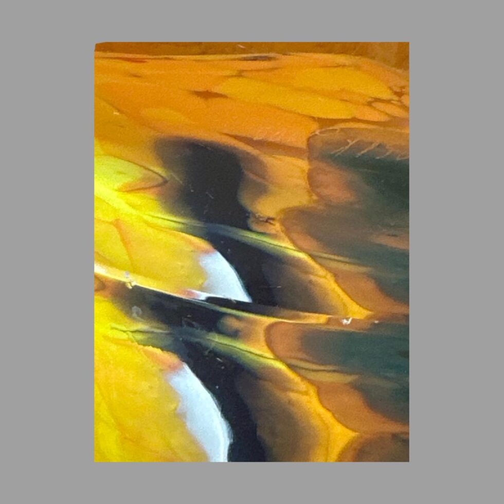 Close up photo of the merging colours within one part of the glass - here we have orange, yellow, black jagged strips with white highlights.
