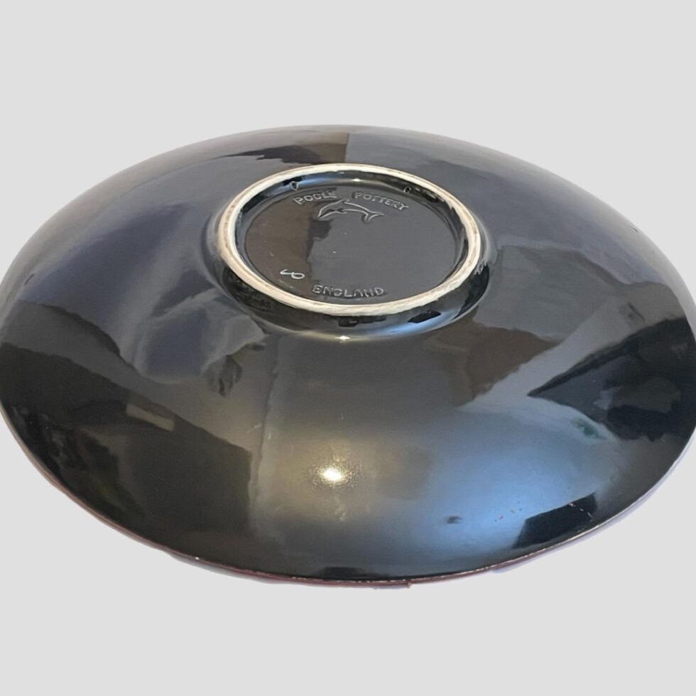 Photo of the back of Poole Himalayan poppy charge showing a glossy slate black glaze. There are quite a few things reflected in the glossy glaze - not a defect!