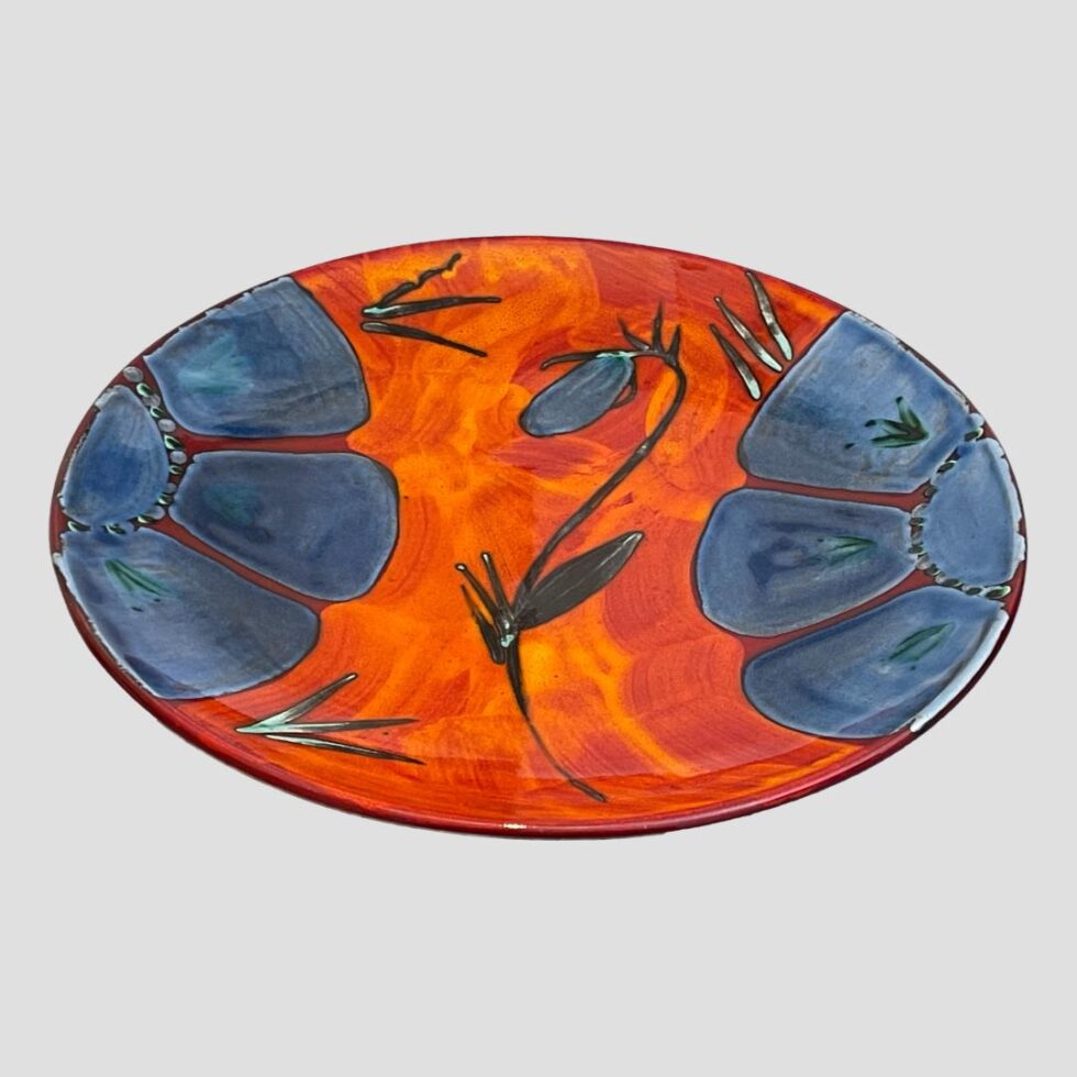 Photo of Poole poppy charger displayed on a flat surface looking diagonally down.