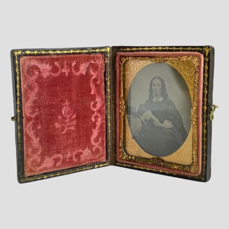 Main photo of c1850 Victorian daguerreotype displayed upright and open revealing the plush dark pink velvet to the left and the striking image of a handsome Victorian lady to the right.