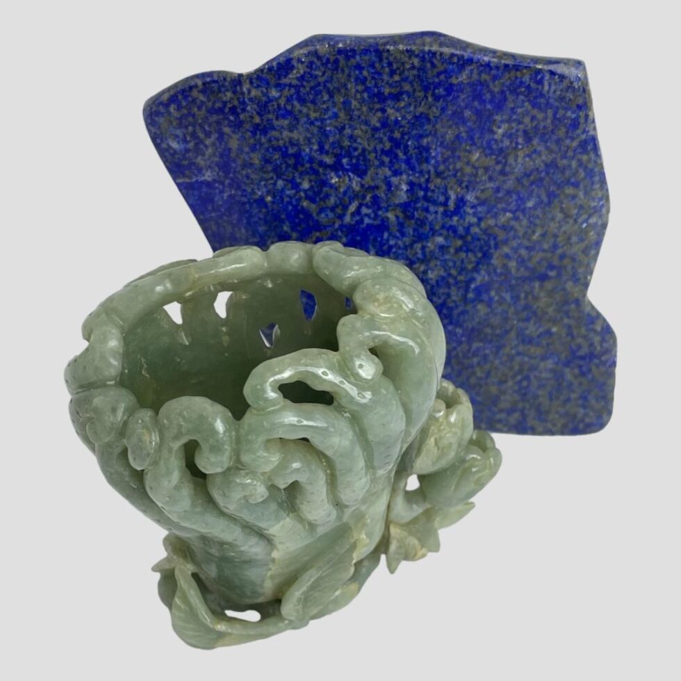 Photo of jadeite calligraphy water pot seen from a slightly raised height peering into the mouth. The piece of lapis is still in the background to the right.