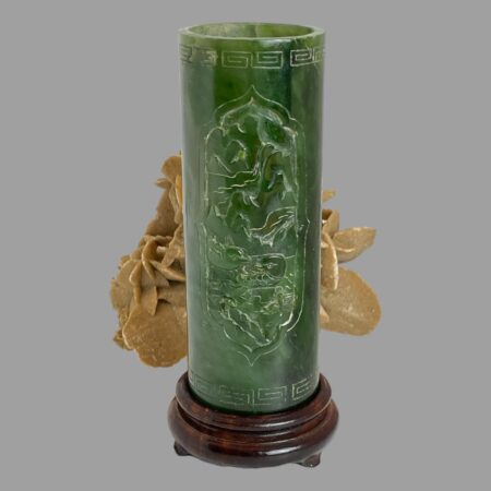 Main photo of jade brush pot &stand displayed standing on its dark lacquered wood stand and with the carved scene side on show. The spinach green jade and dark wood stand are very complimentary together. There is a rock of natural desert sand rose in thew background.